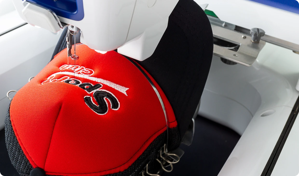 Embroidery machine stitching a red sports cap.